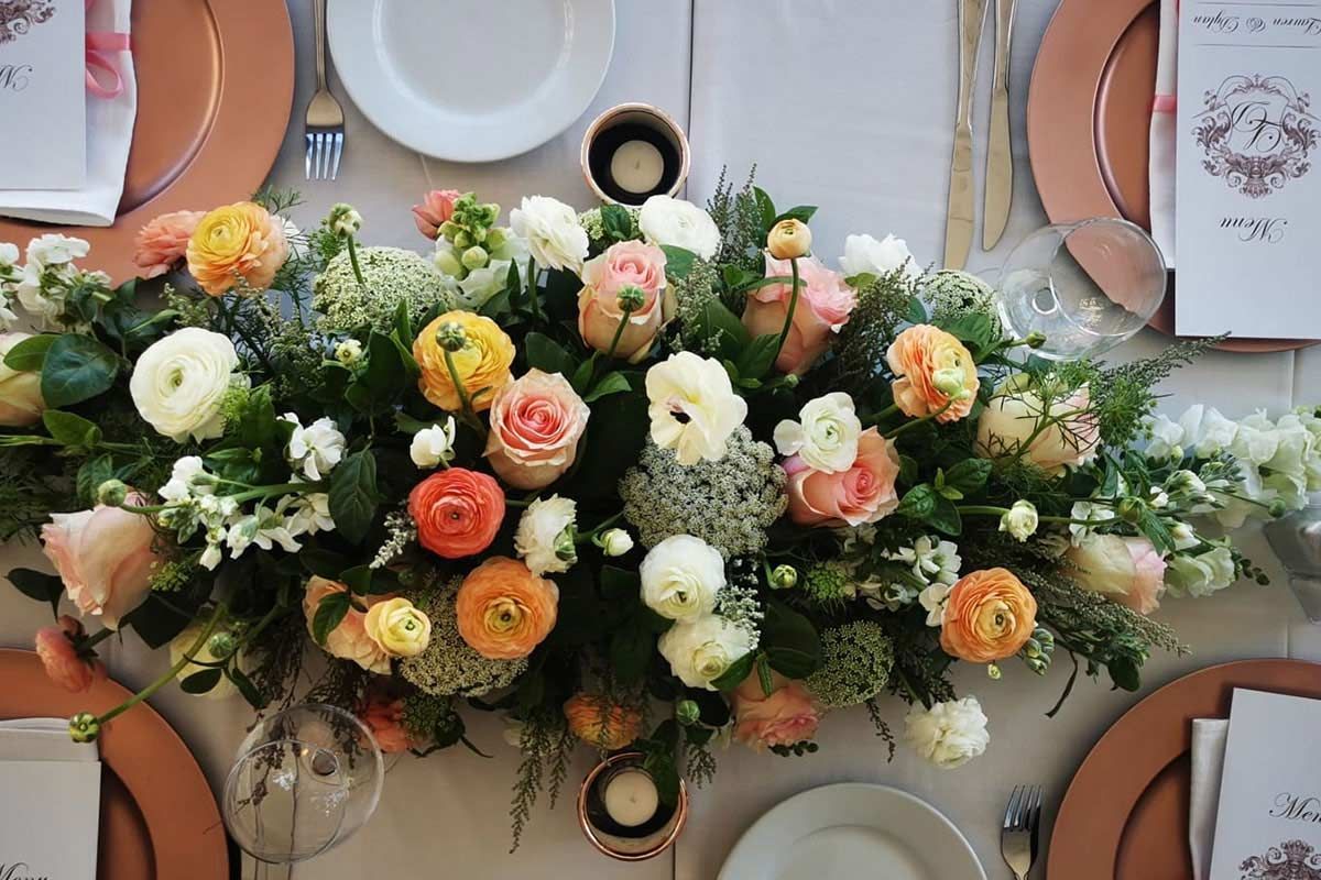 A table with plates , napkins , and flowers on it.