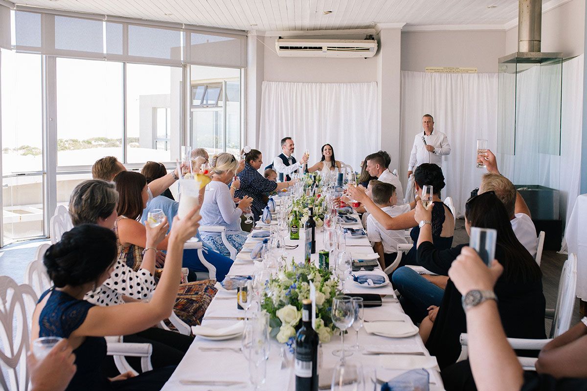 A group of people are sitting at a long table toasting with champagne.
