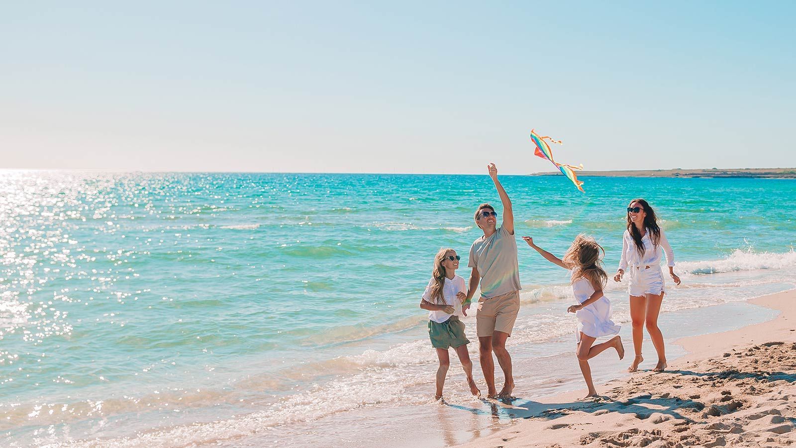 Eine Familie lässt am Strand einen Drachen steigen.