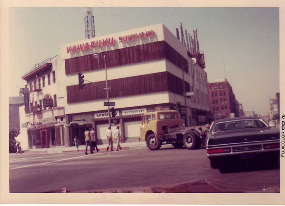 A black car is parked in front of a building that says ' maharaja ' on it