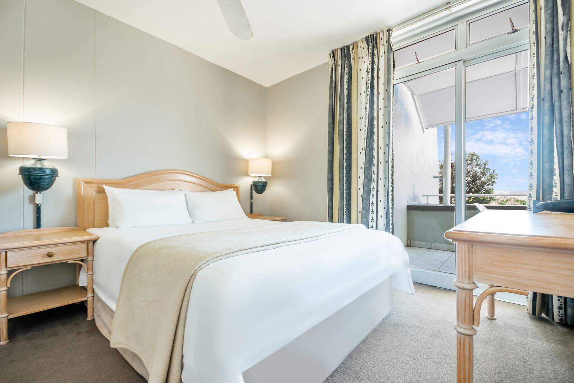 A hotel room with a king size bed and a desk.