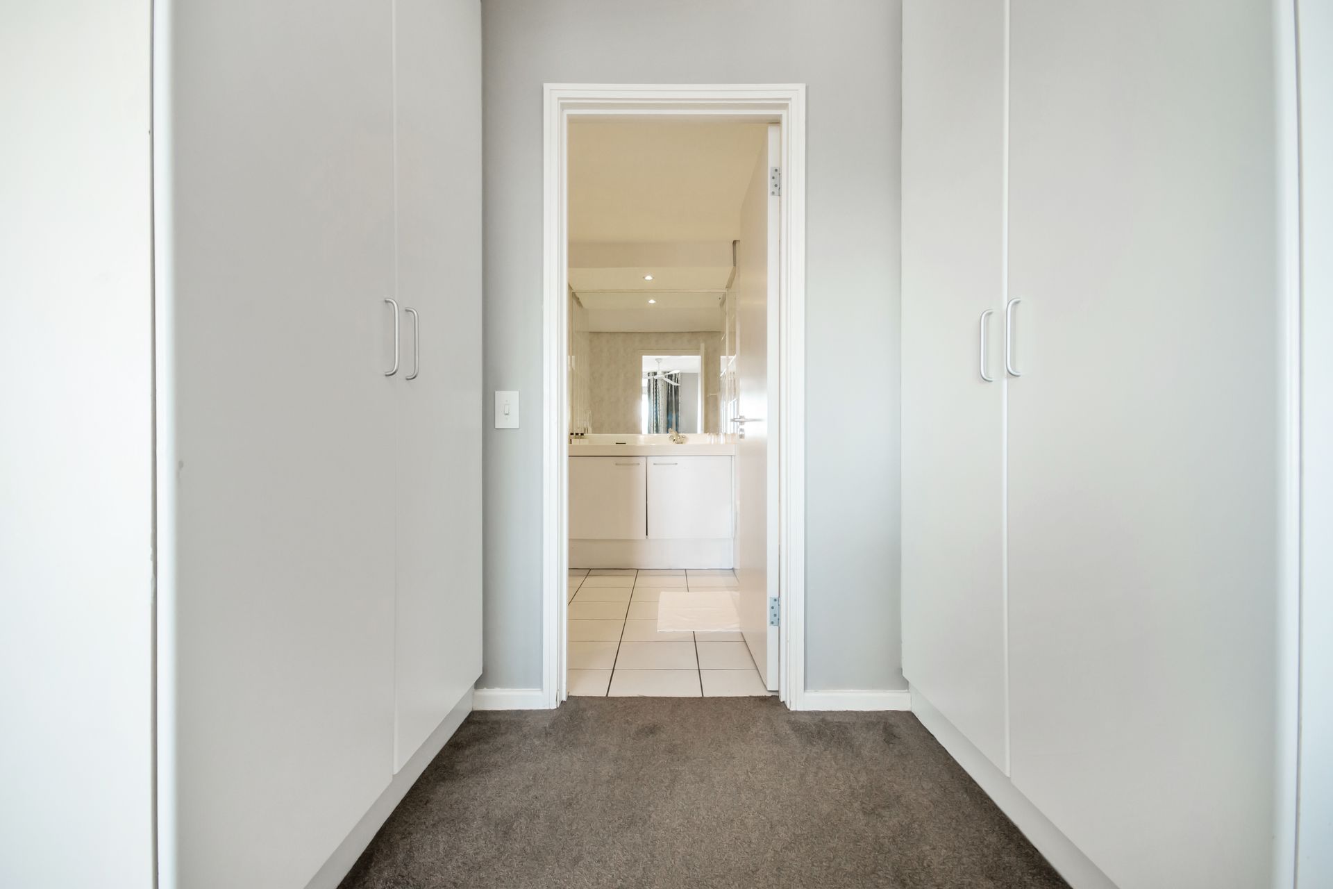 A hallway with a door open leading to a bathroom.