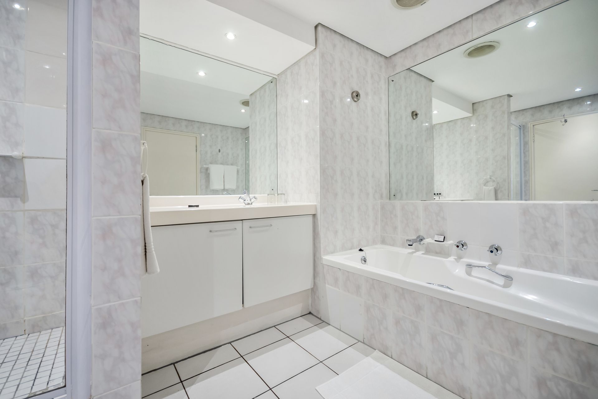 A bathroom with a bathtub , sink and mirror.