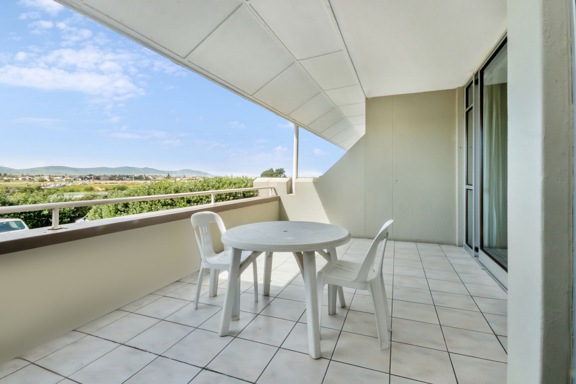 There is a balcony with a table and chairs on it.