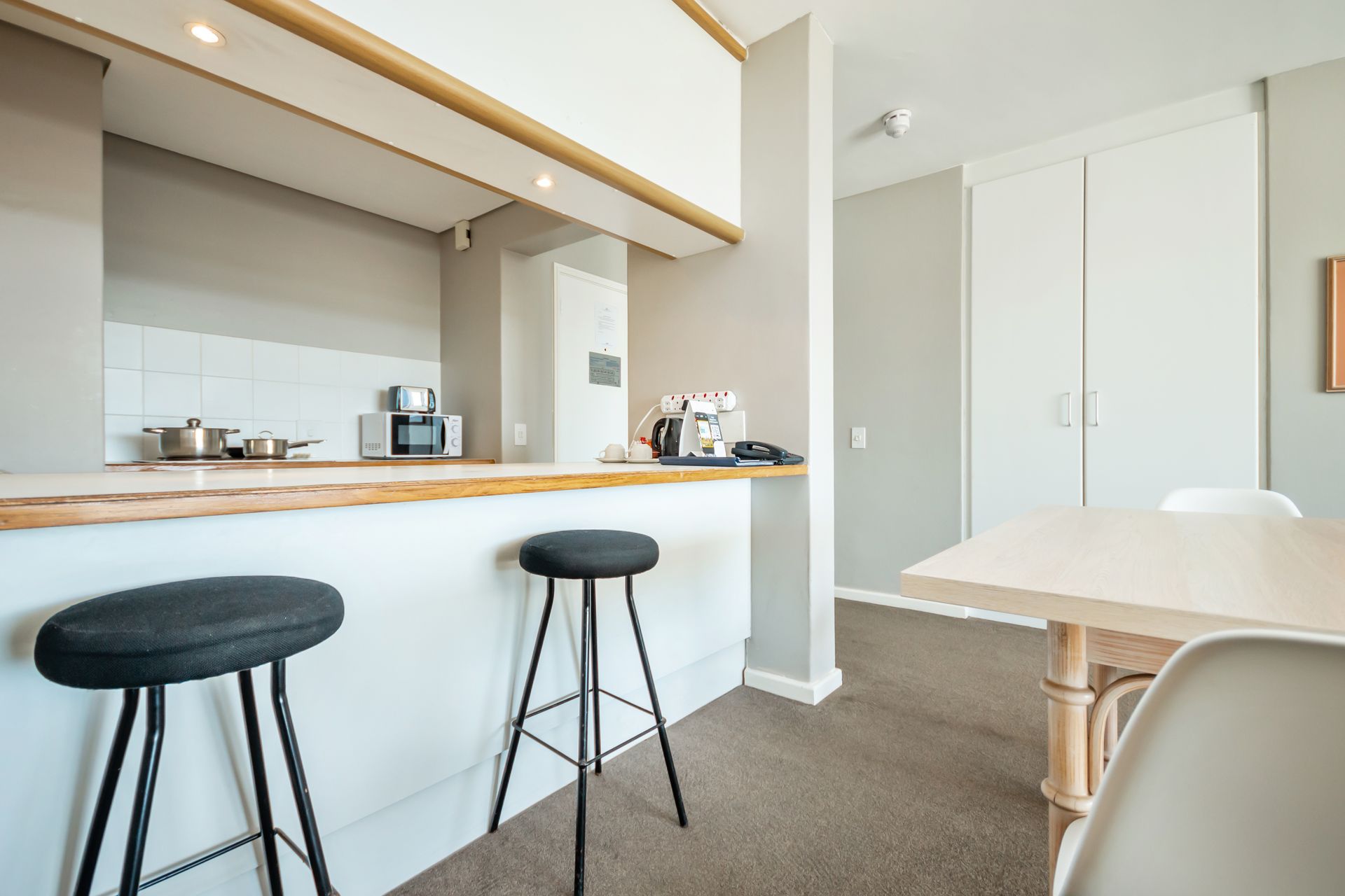 A kitchen with a table and two stools in it.