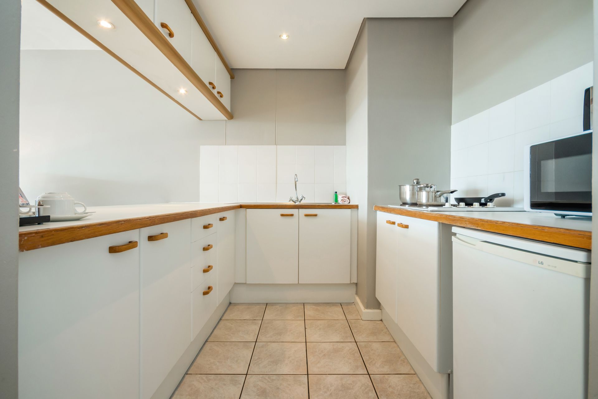 A kitchen with white cabinets and wooden counter tops