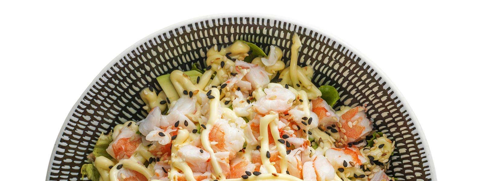 A close up of a bowl of food with shrimp and noodles on a white background.