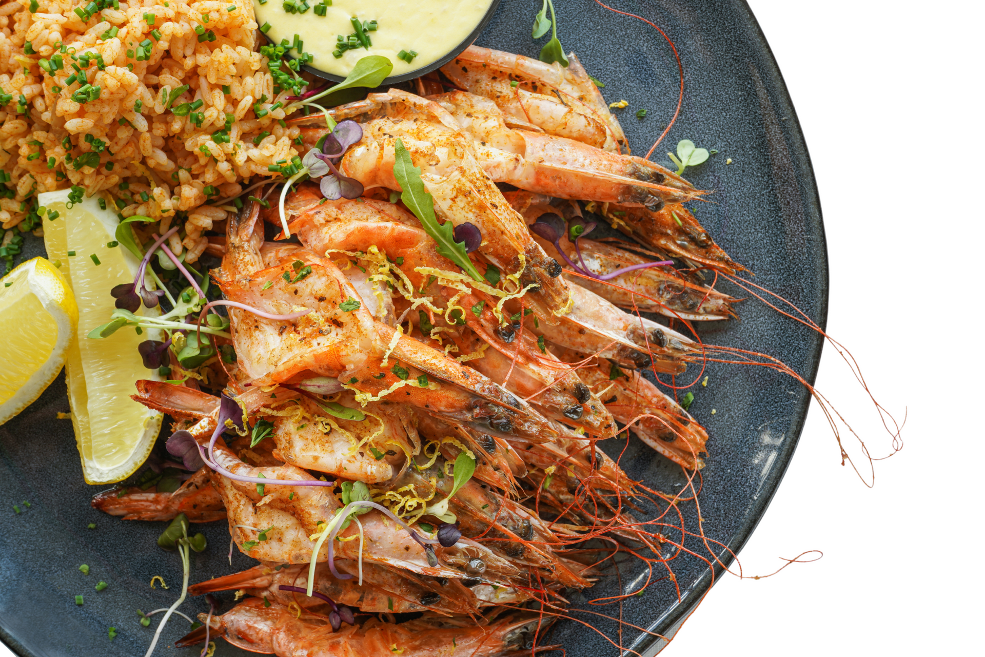 A black plate topped with shrimp , rice and lemon slices.