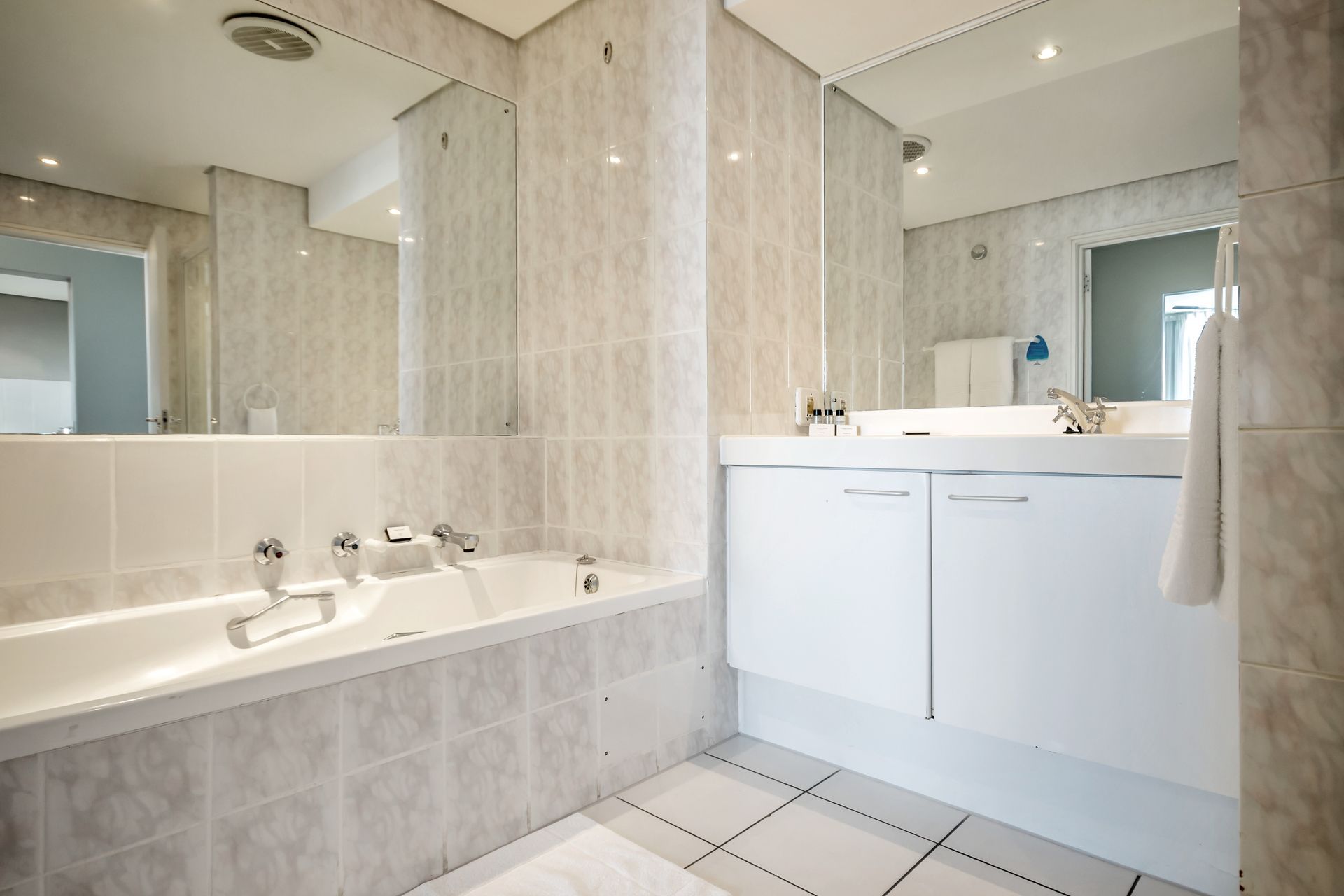 A bathroom with a bathtub , sink and mirror.