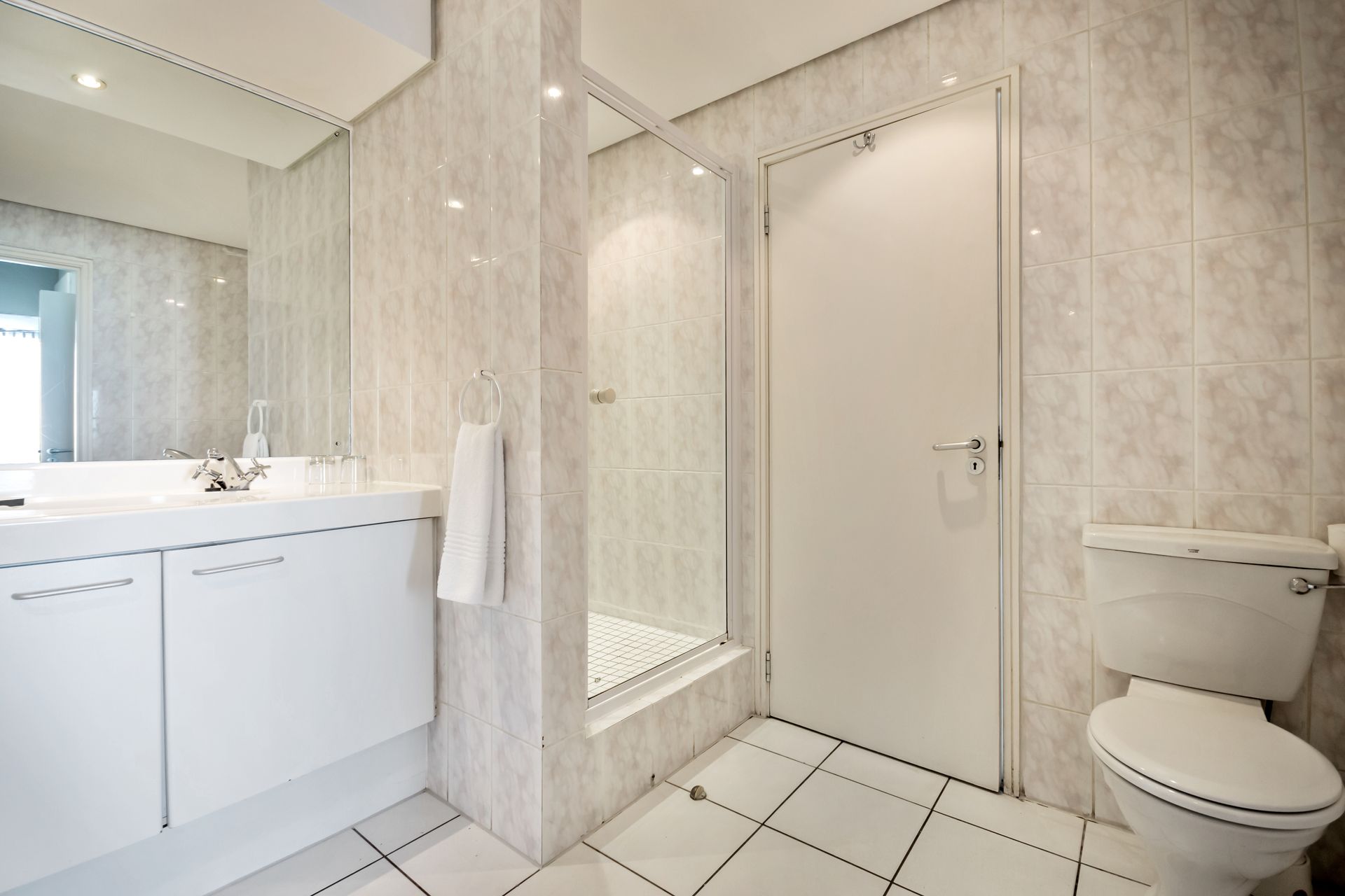 A bathroom with a toilet , sink , mirror and walk in shower.