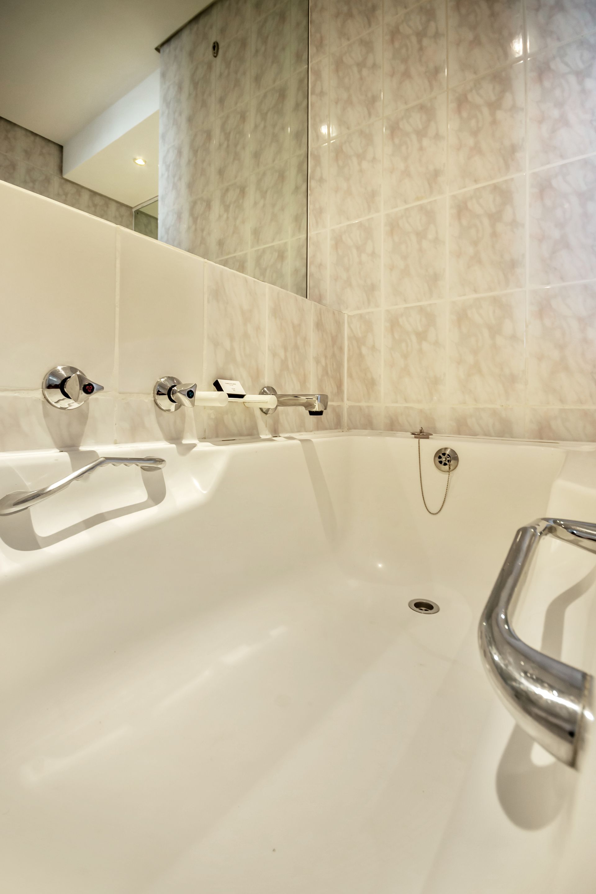 A bathroom with a bathtub and a mirror