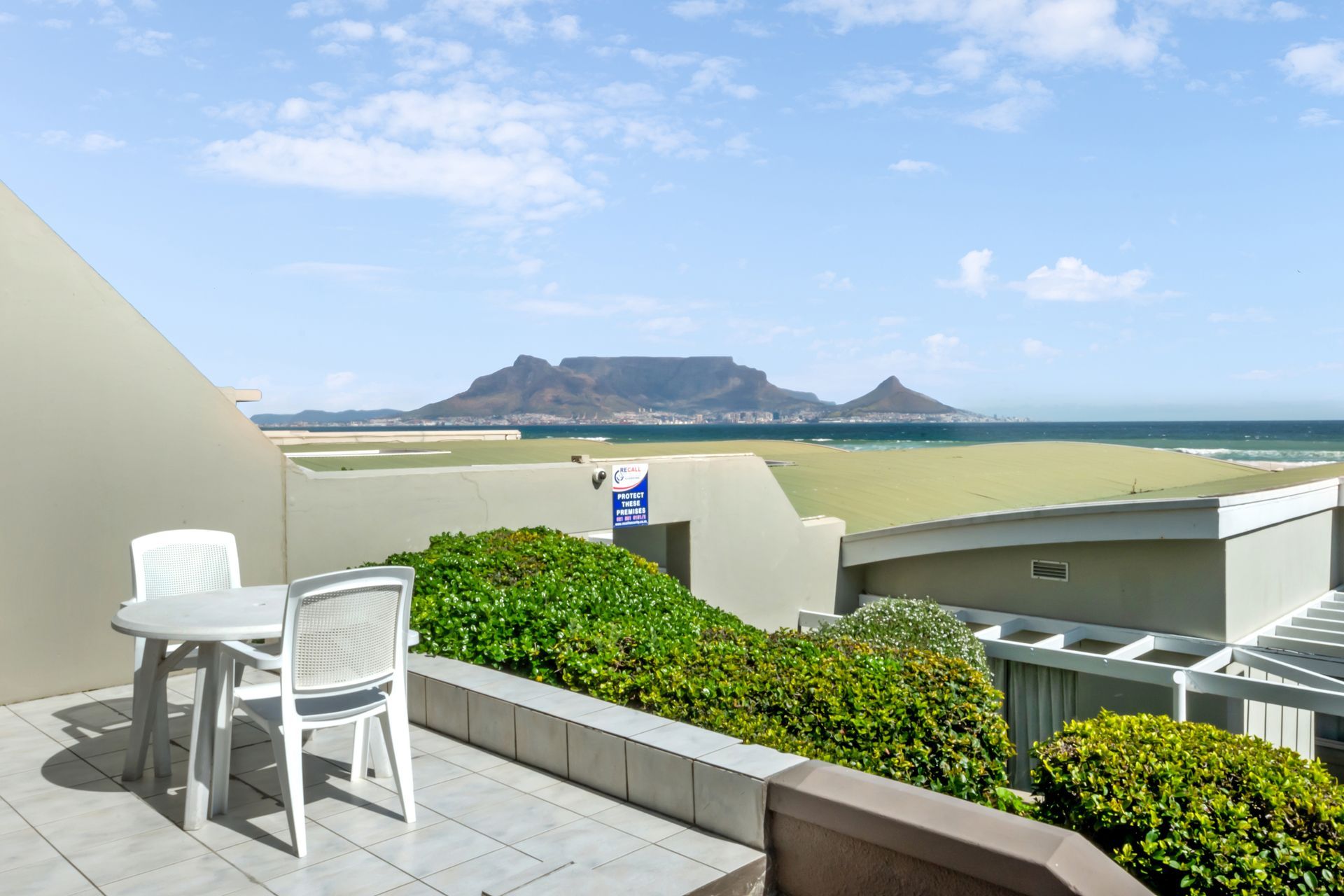 Een balkon met een tafel en stoelen met uitzicht op de oceaan