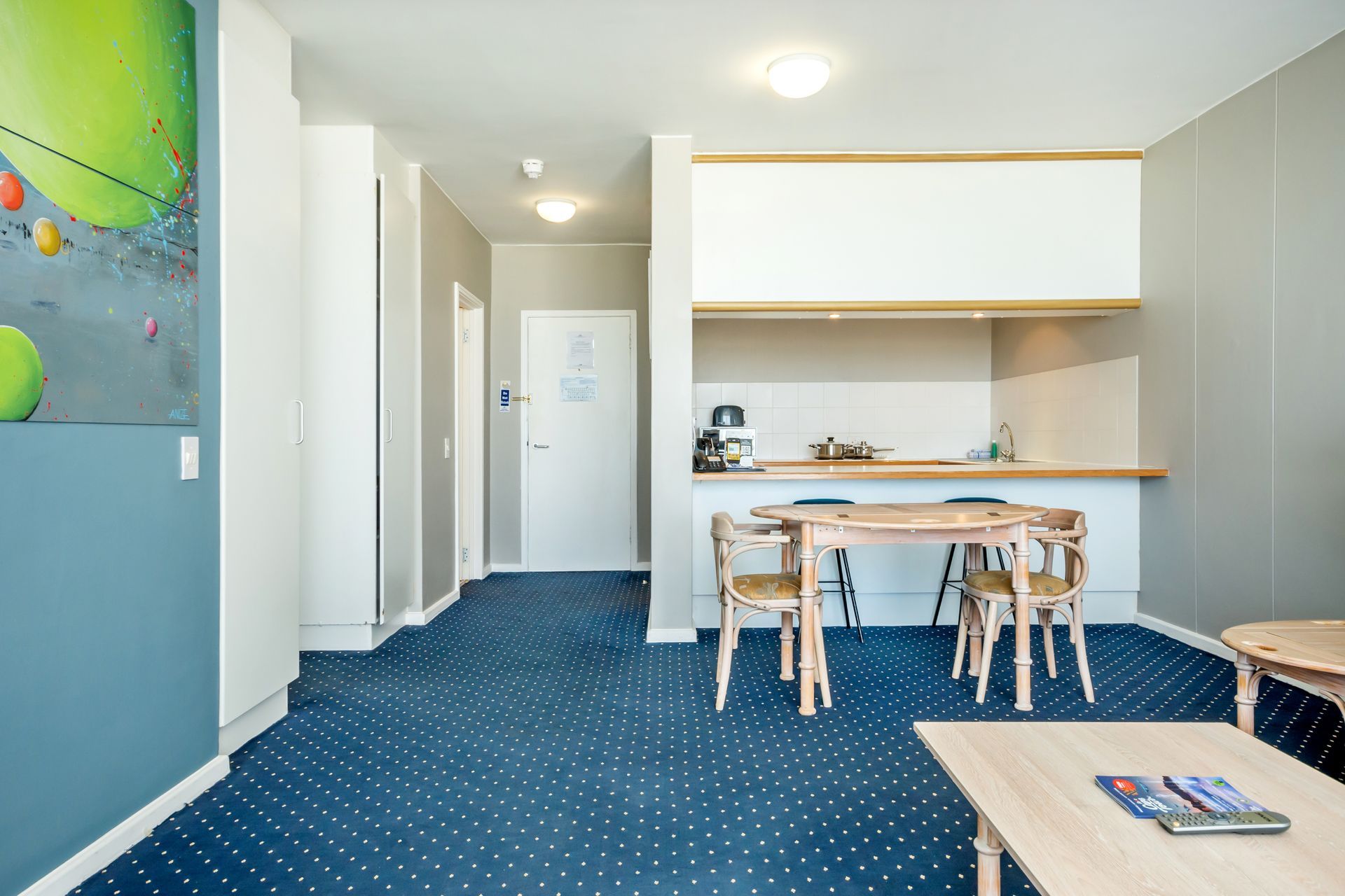 A living room with a blue carpet and a table and chairs