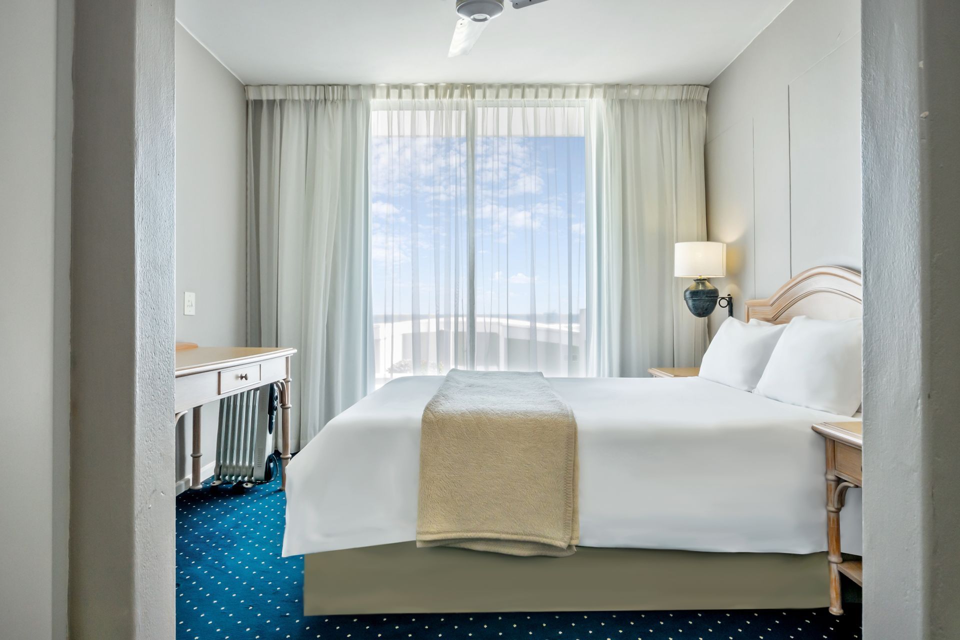 A hotel room with a king size bed and a balcony.