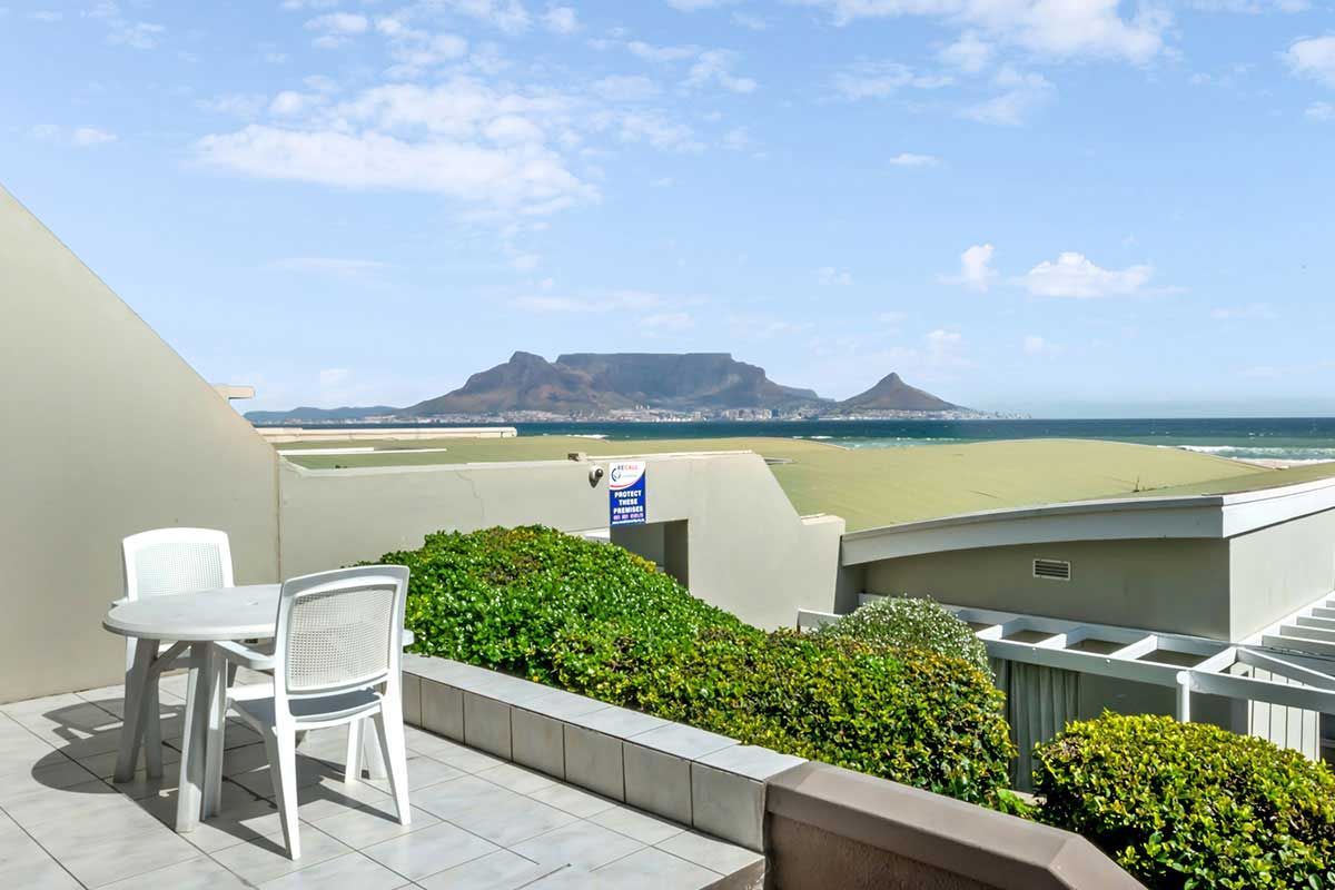 Ein Balkon mit Tisch und Stühlen mit Blick auf das Meer.