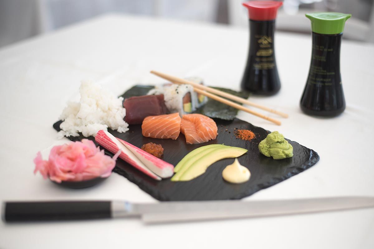 Ein Teller Sushi mit Stäbchen und Saucen auf einem Tisch.