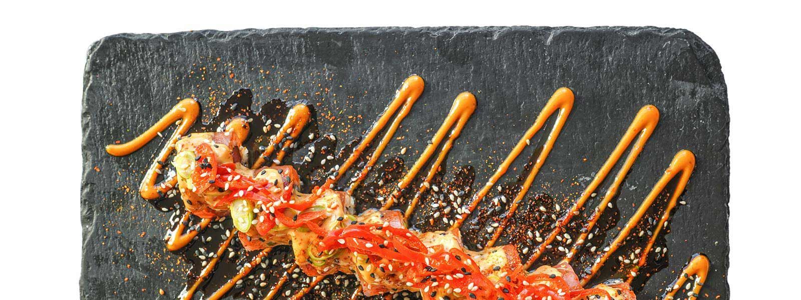 A black plate topped with food and sauce on a white background.