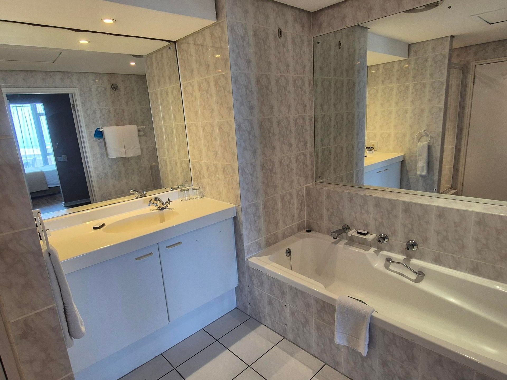 A bathroom with a bathtub , sink and mirror.