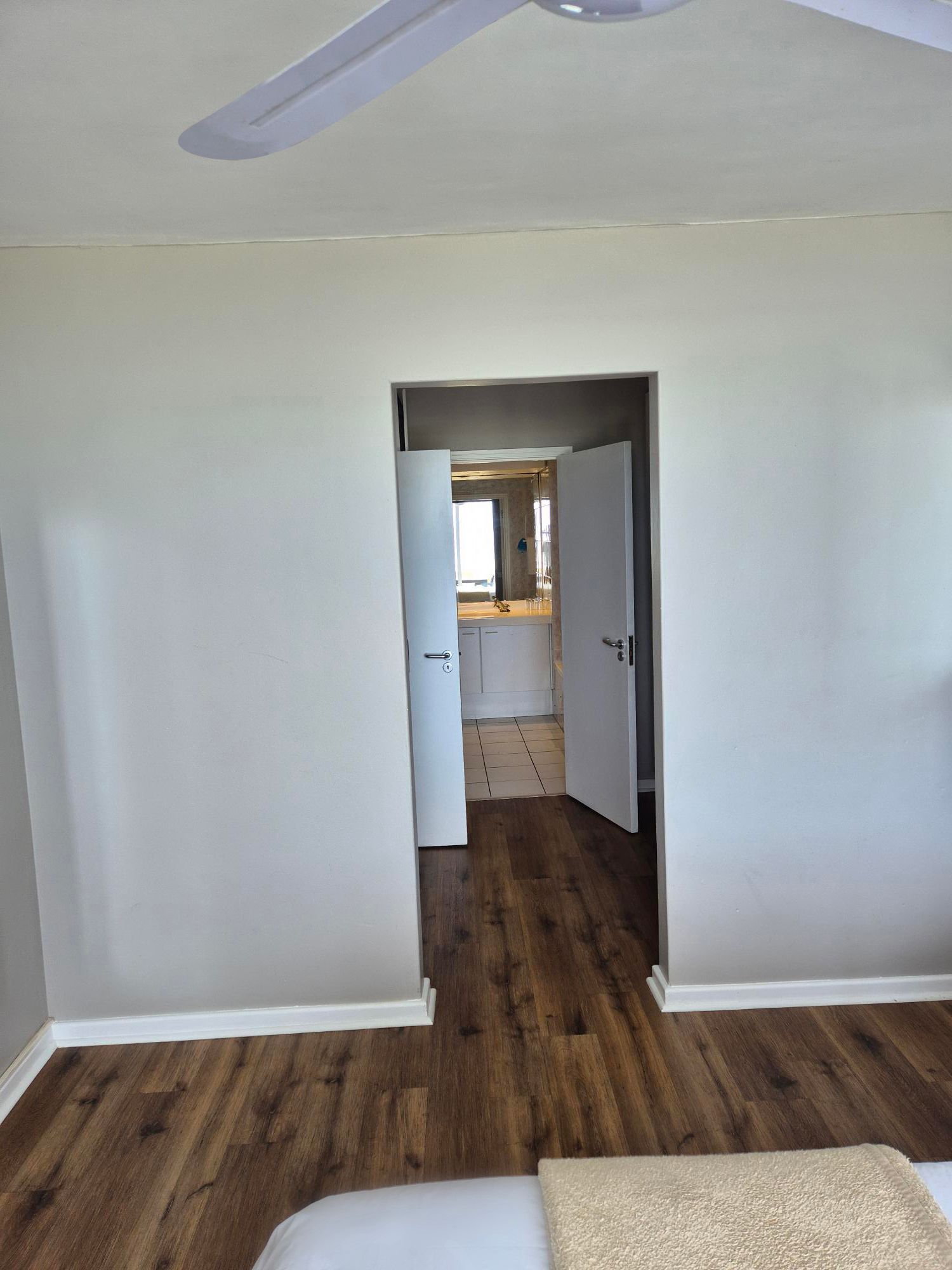 A bedroom with hardwood floors and a ceiling fan.