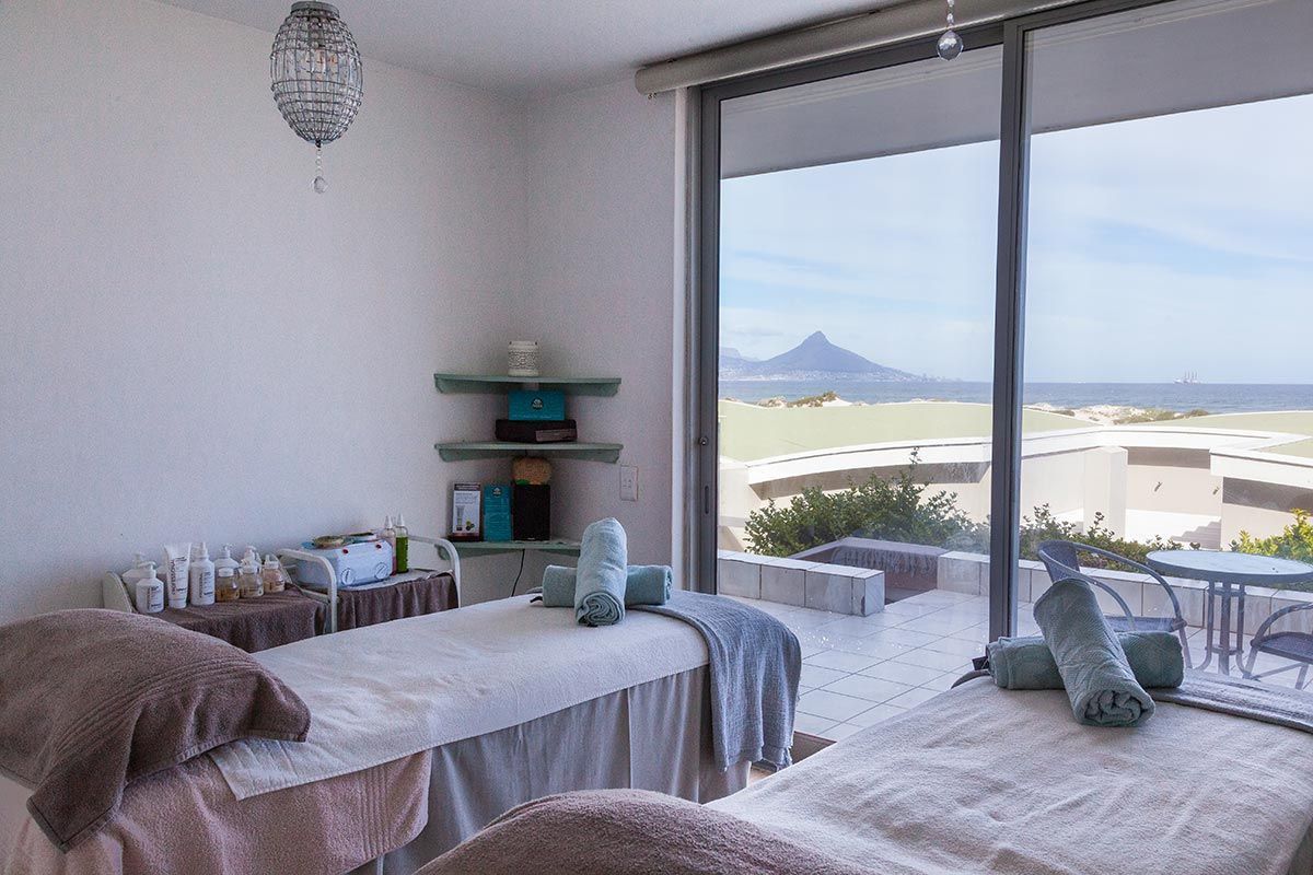 There are two massage tables in a room with a view of the ocean.