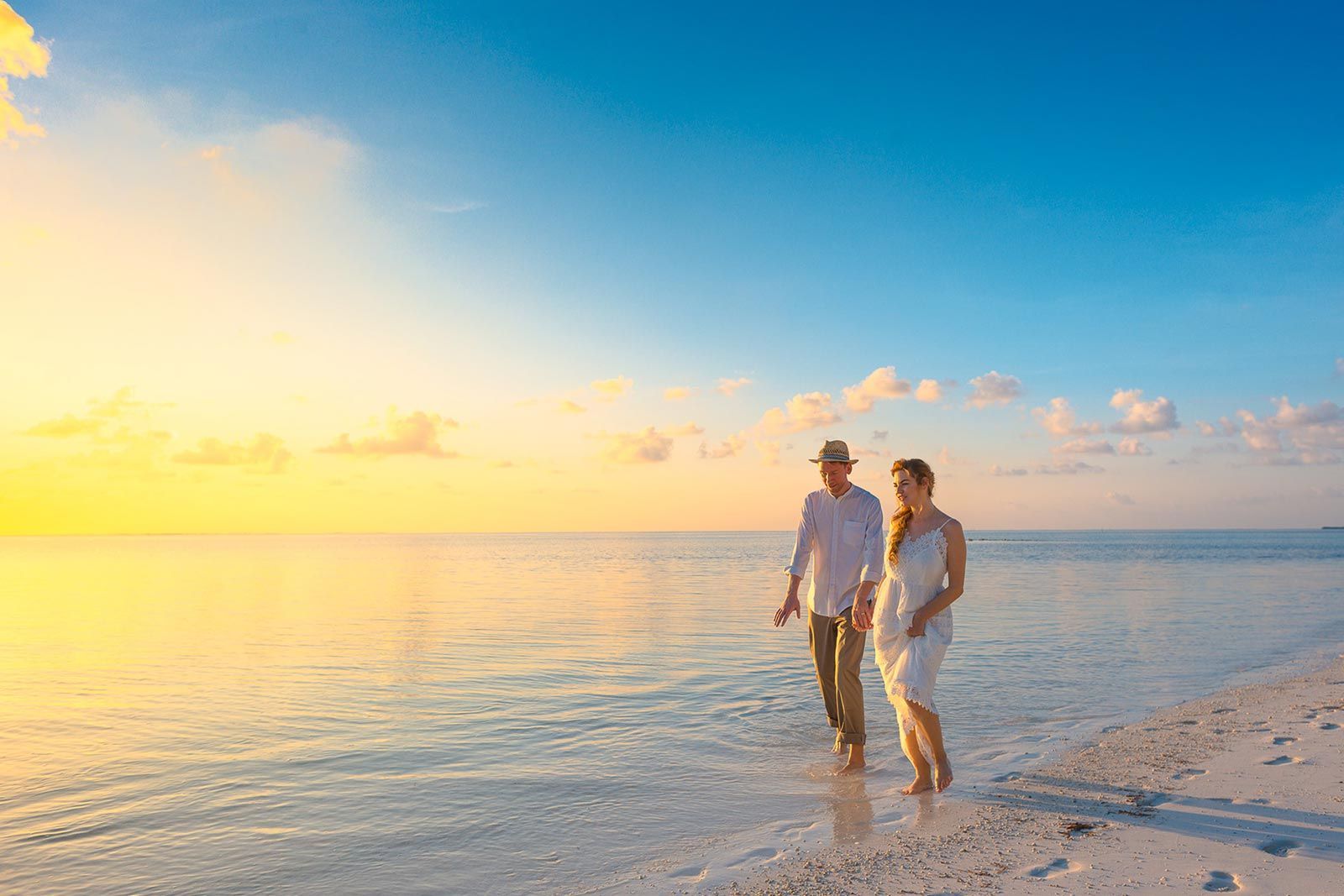 Un uomo e una donna camminano sulla spiaggia al tramonto.