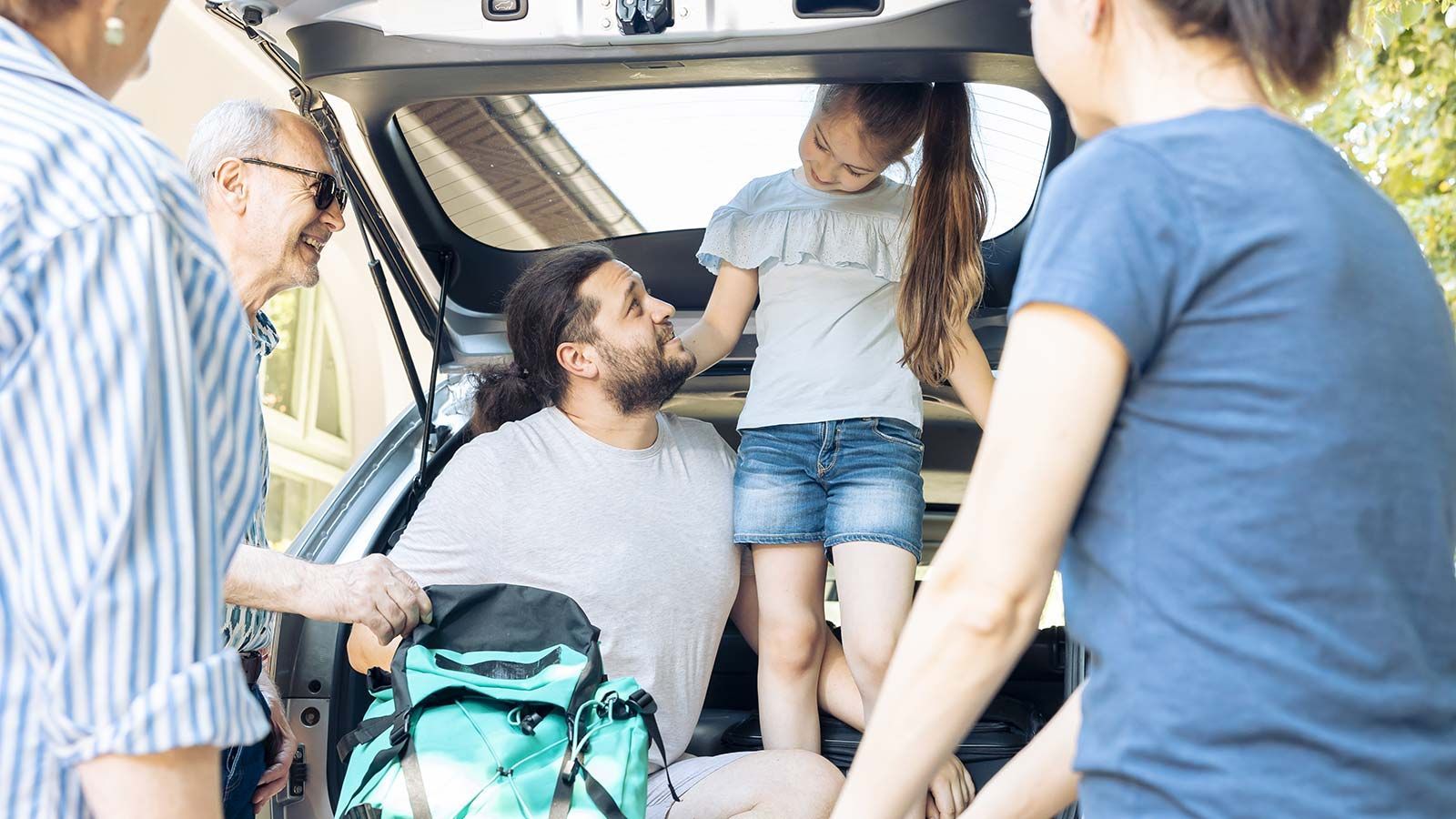 Een gezin laadt hun bagage in de laadbak van een auto.