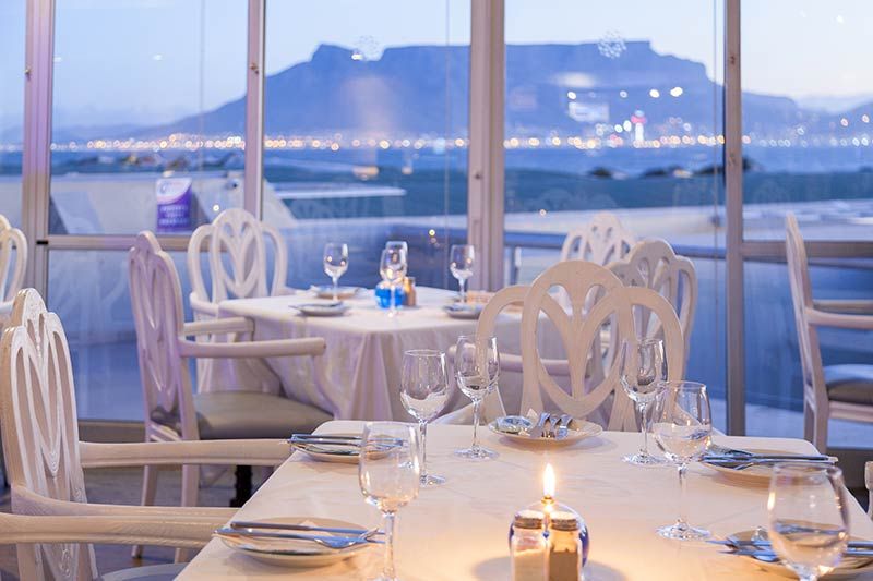 Un restaurante con vista al mar y una montaña al fondo.