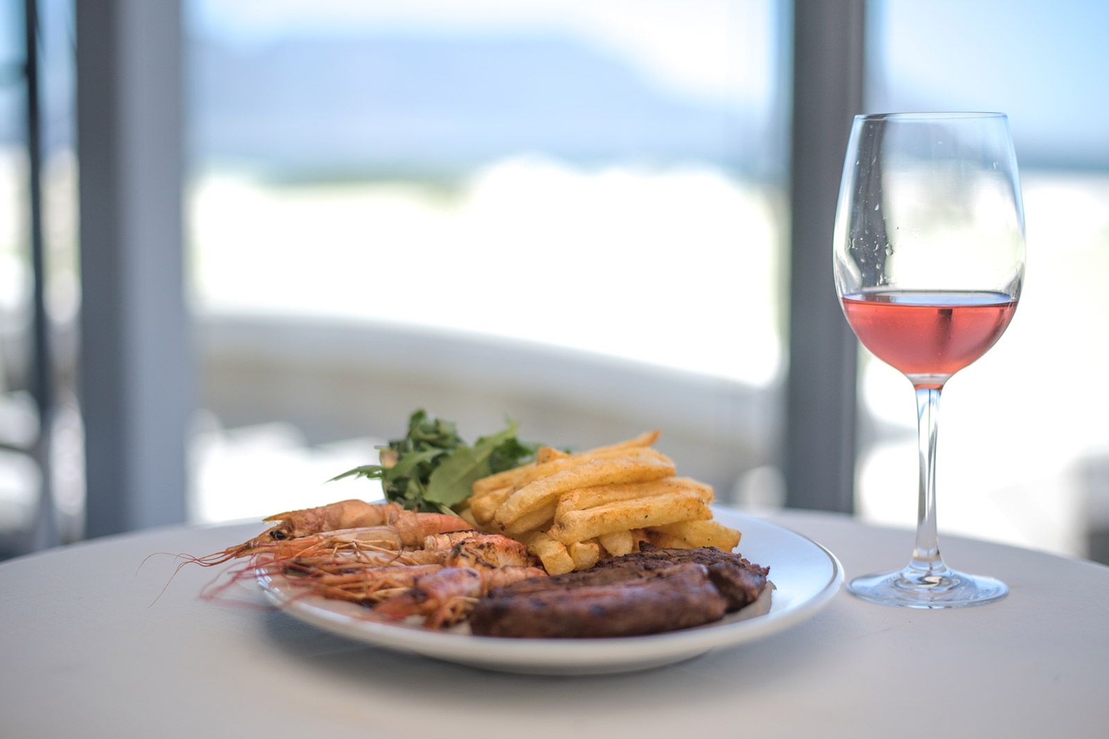 A plate of food and a glass of wine on a table.