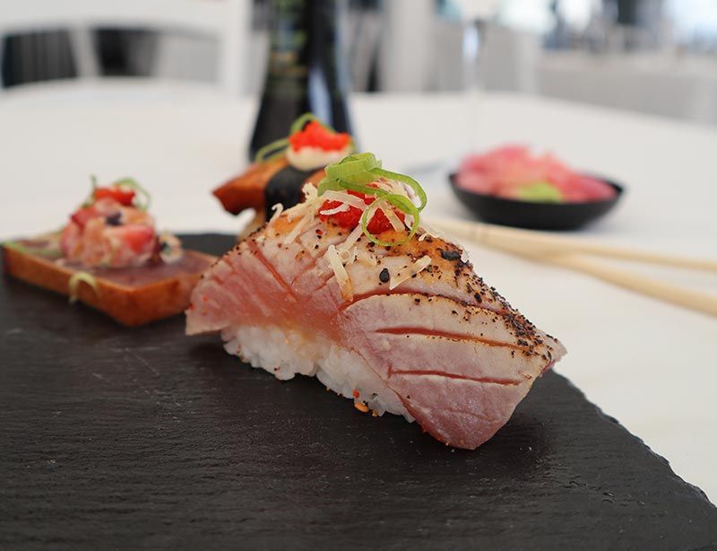 A close up of a piece of sushi on a plate with chopsticks.