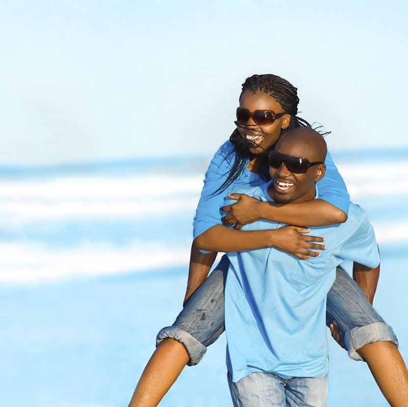 A man is carrying a woman on his back at the beach