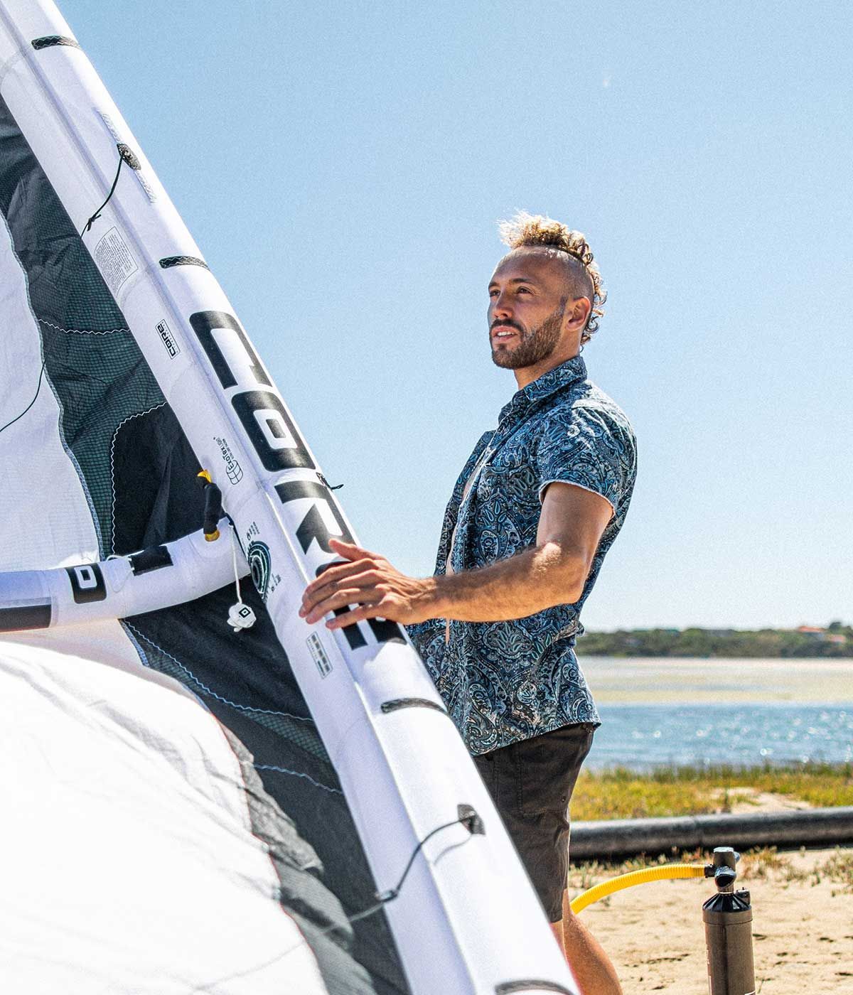 A man is standing next to a large sail that says lgk on it