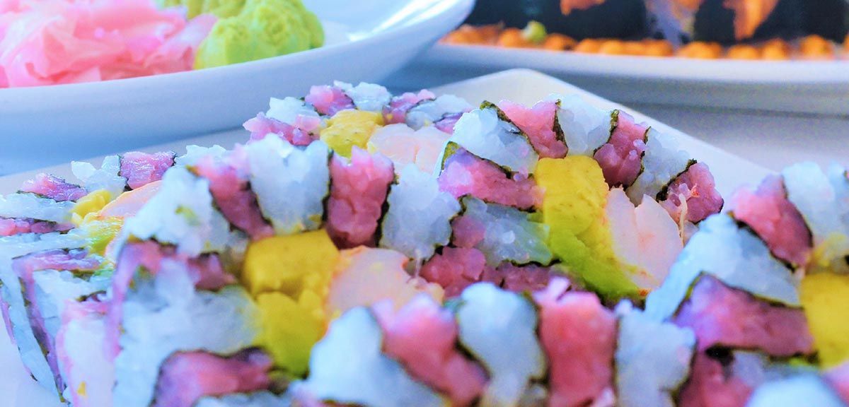 Een close-up van een bord met kleurrijke sushi op een tafel.