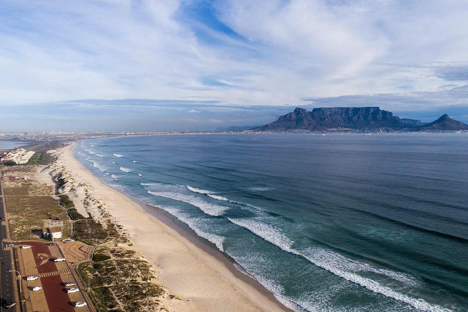 Eine Luftaufnahme eines Strandes mit einem Berg im Hintergrund.