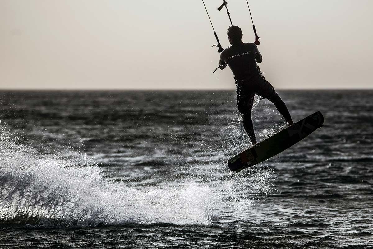 A person is flying through the air on a surfboard in the ocean.