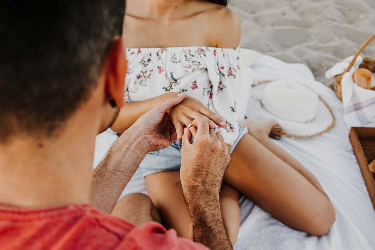 Een man schuift een verlovingsring om de vinger van een vrouw.