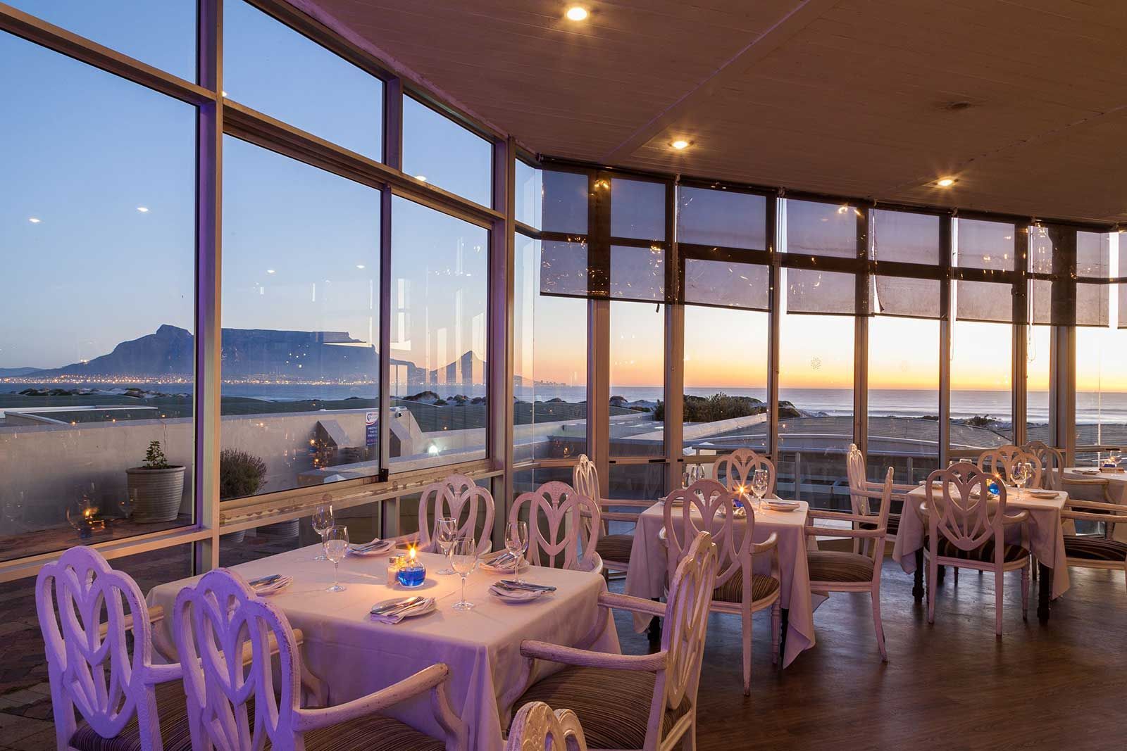 A restaurant with tables and chairs and a view of the ocean.