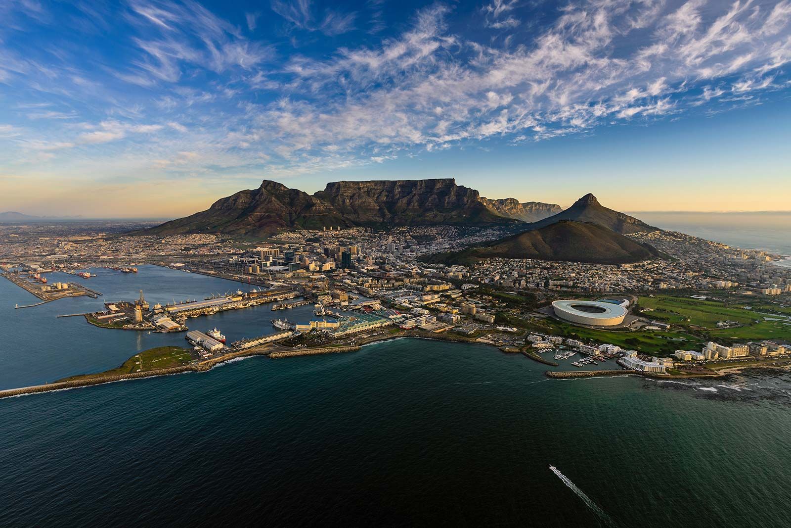 An aerial view of a city with a mountain in the background and a body of water in the foreground.