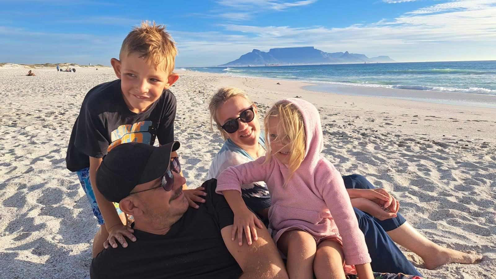 A family is posing for a picture on the beach.