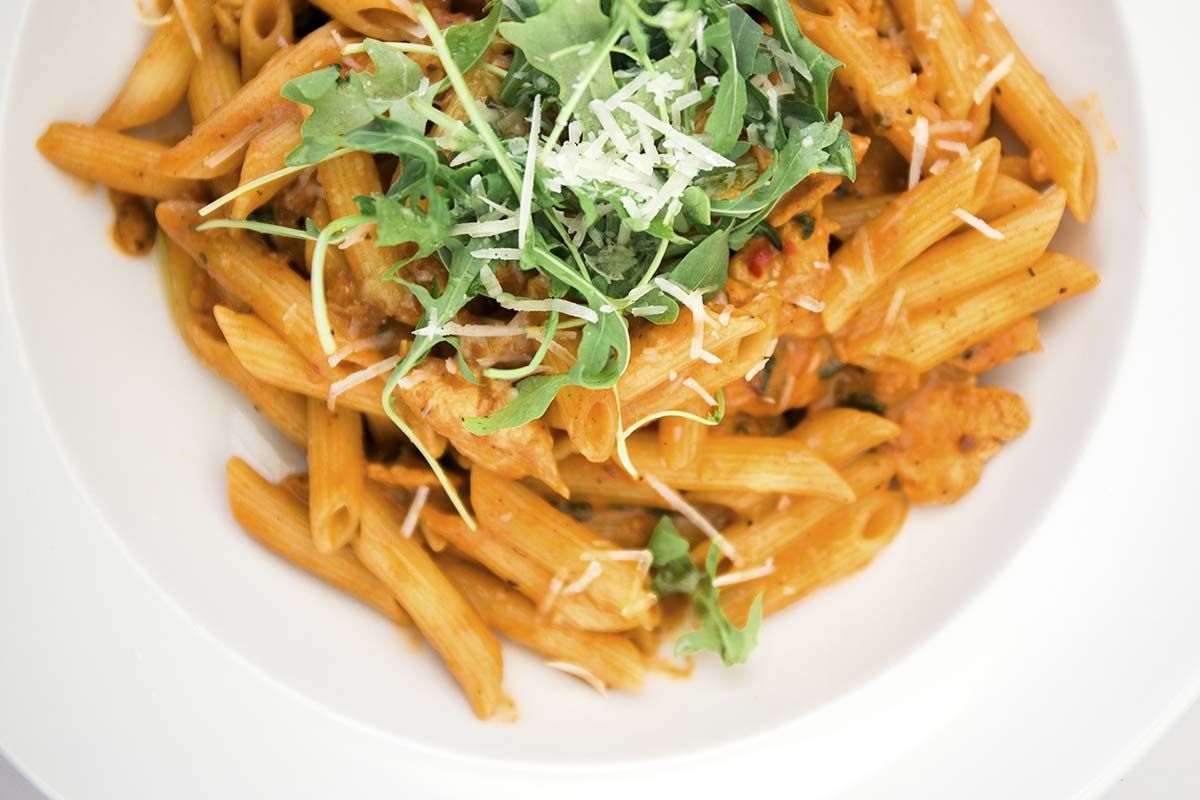 Een close-up van een bord pasta met saus en kaas op een tafel.