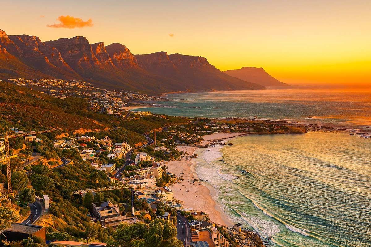 An aerial view of a beach at sunset with mountains in the background.