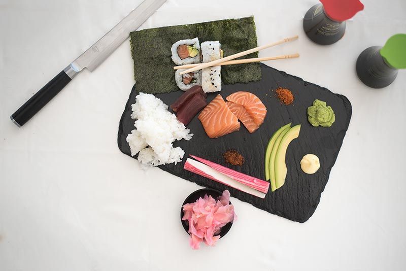 A cutting board filled with sushi and chopsticks on a table.