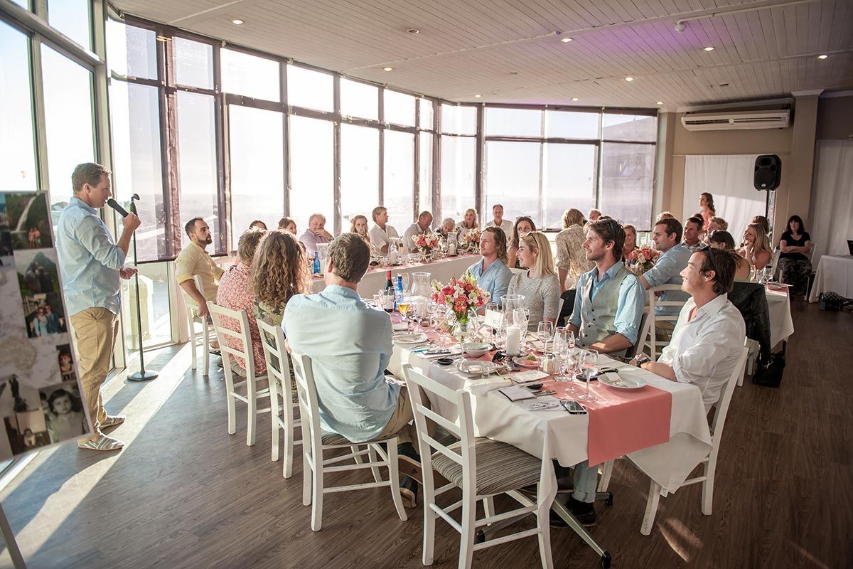 A man is giving a speech to a large group of people sitting at tables.