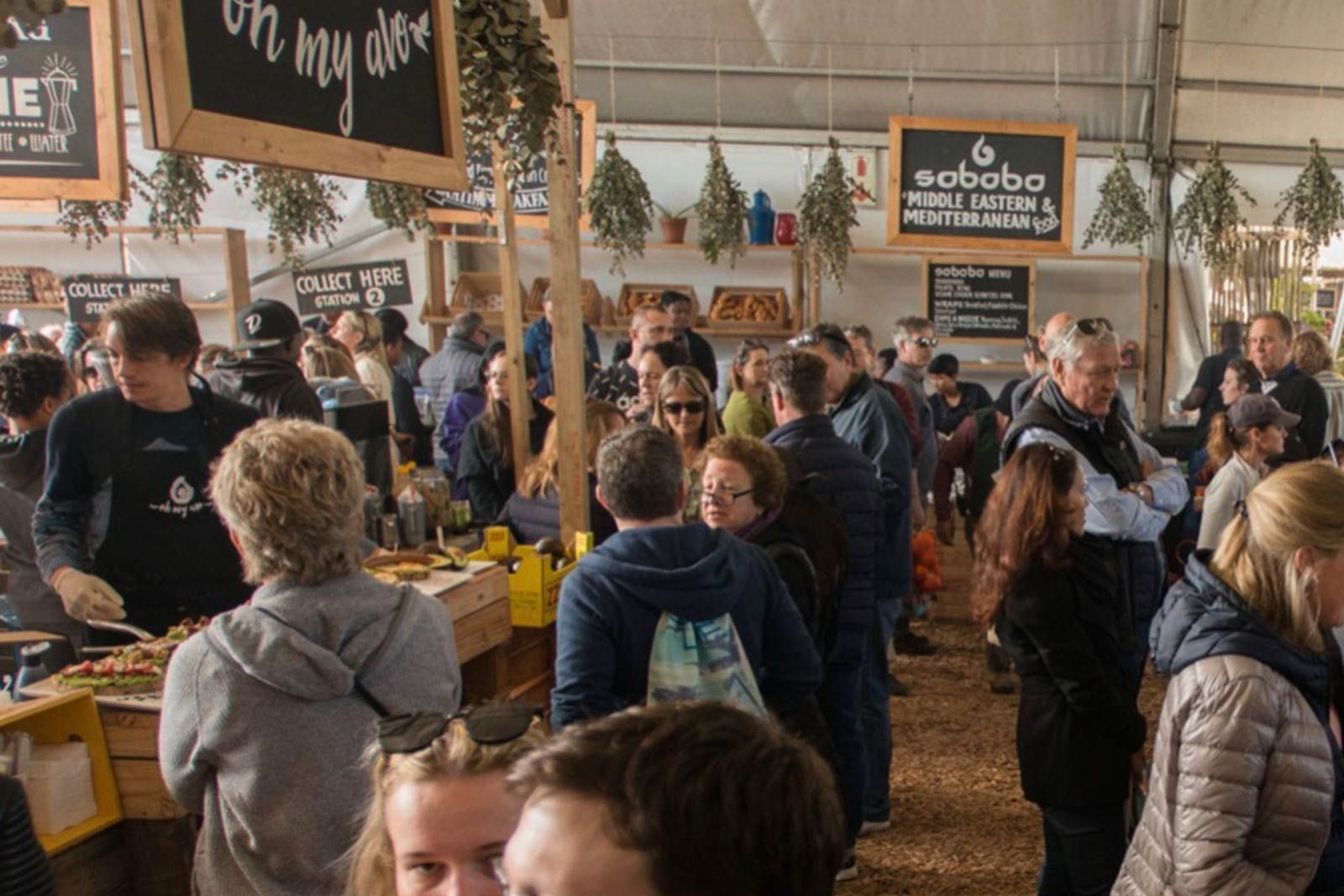 Een groep mensen staat rond een eetkraam op een festival.