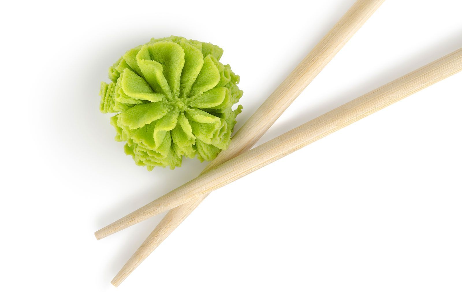 A pair of chopsticks and a ball of green wasabi on a white background