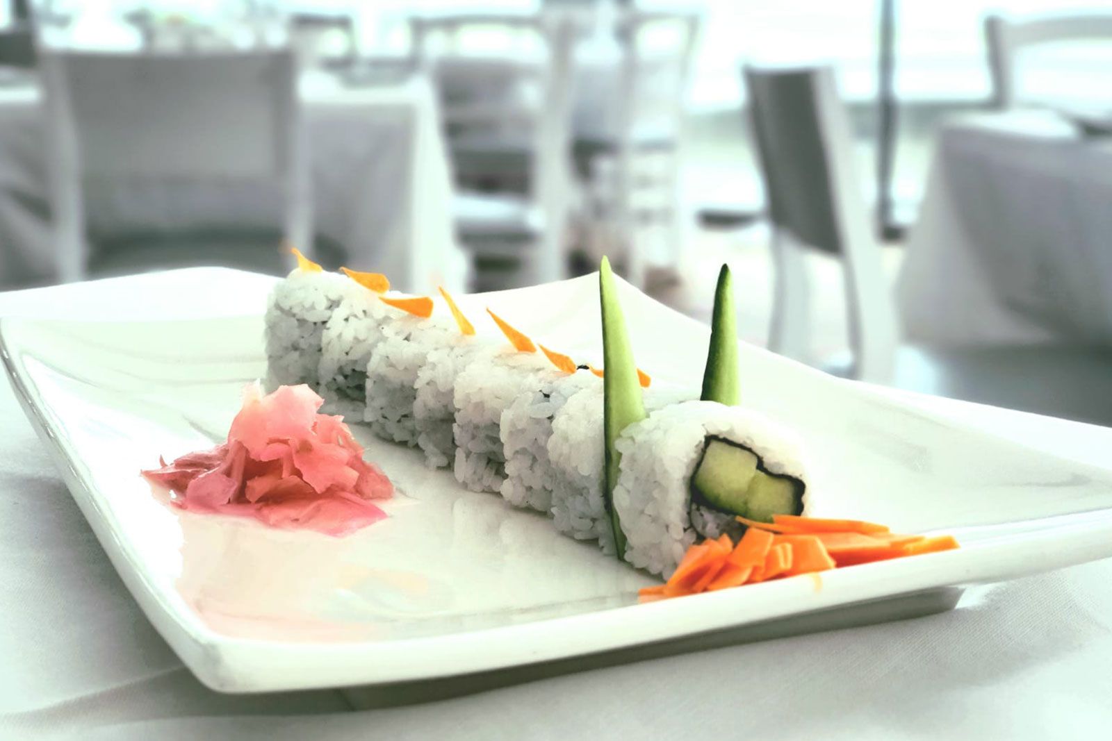 A white plate topped with sushi and vegetables on a table.