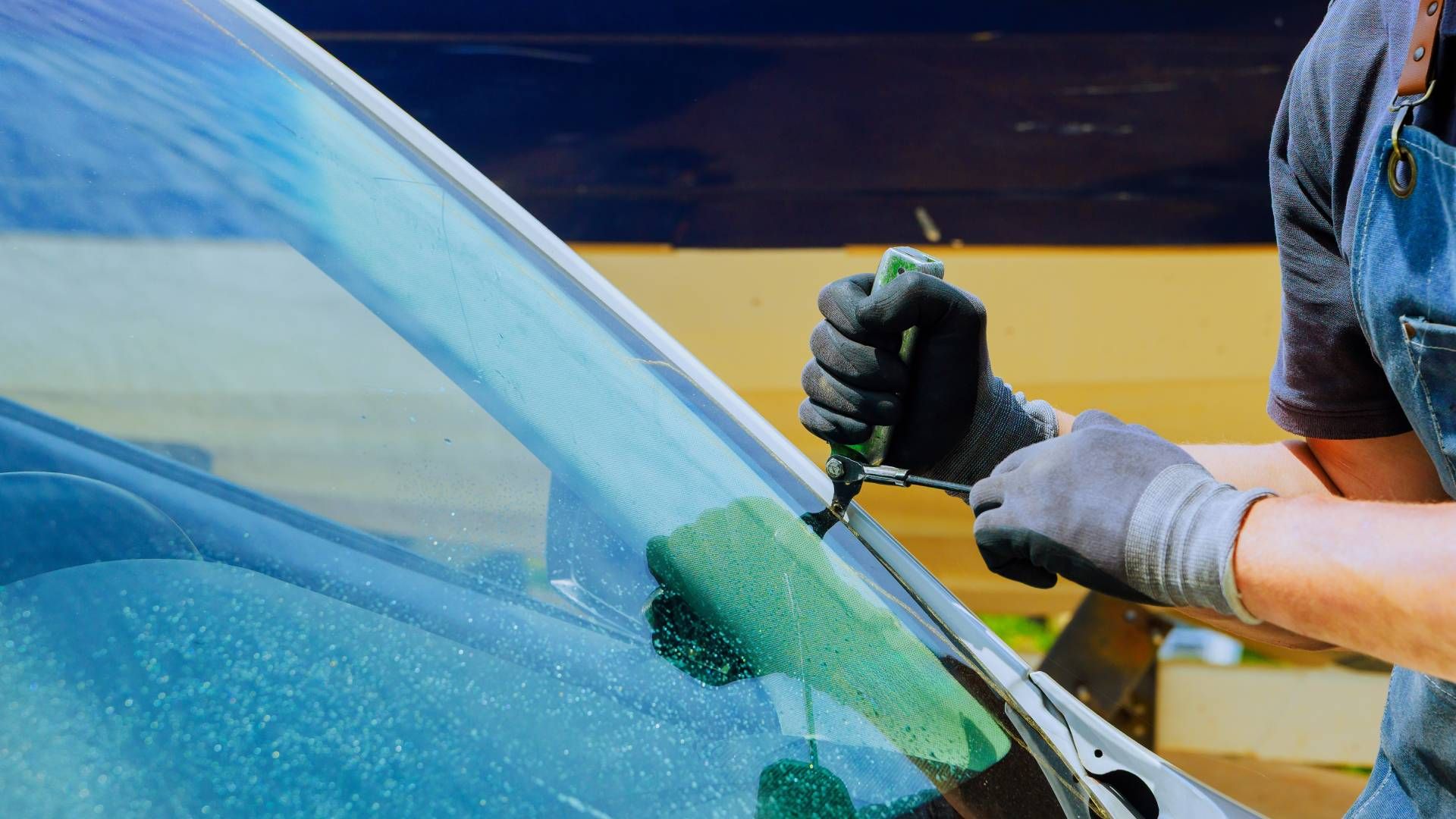 A person is fixing a windshield on a car.
