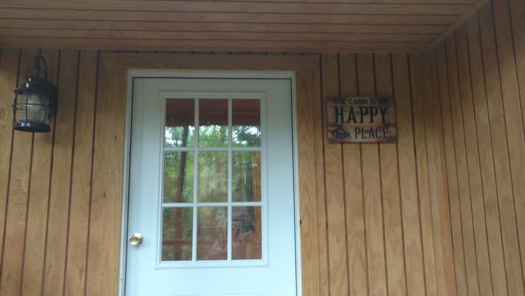 White door with glass panes on a wood paneled wall, with a 