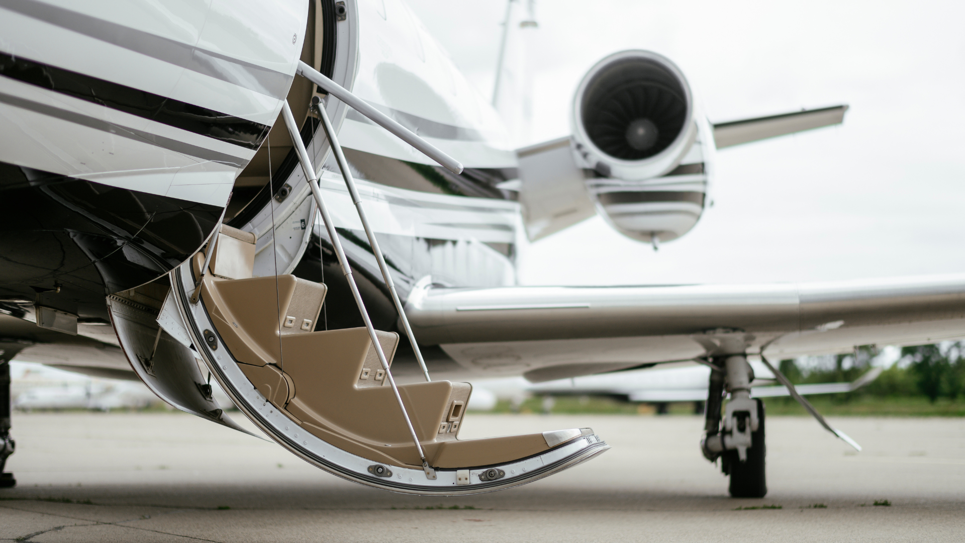 A private jet with stairs leading up to it is parked on the tarmac.