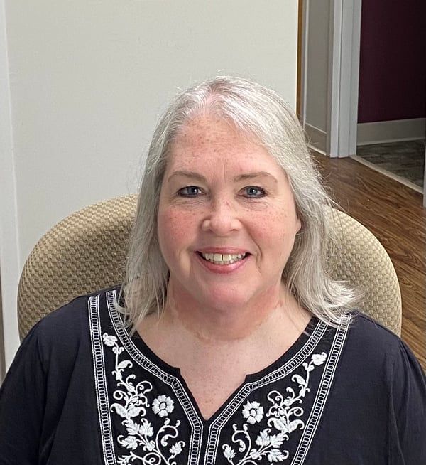 A woman is sitting in a chair and smiling for the camera.