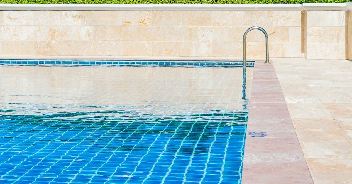 A swimming pool with blue tiles and a metal ladder.